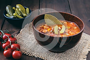 Bowl with Solyanka, a spicy and sour soup of Russian origin, on dark wooden table