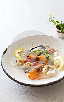 Bowl of soup with cod, mussels, shrimps and coconut milk close up