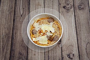 A bowl of spaghetti bolognese with tomato, beef meatballs, lacquers of Parmesan cheese in a delivery bowl