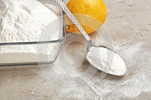 Bowl and spoon of baking soda with lemon on gray table