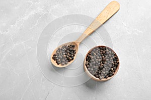 Bowl and spoon with black peppercorns on marble table