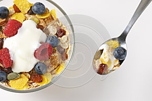 Bowl and spoon of cereals with berry fruit and white yogurt