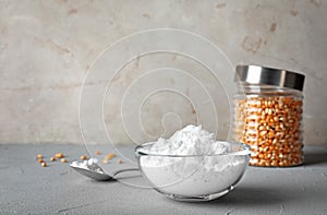 Bowl and spoon with corn starch on grey table