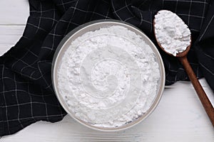 Bowl and spoon of starch on white wooden table, top view