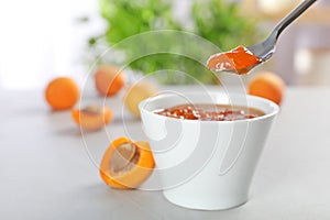 Bowl and spoon with tasty apricot jam