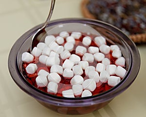 a bowl of strawberry and bananas gelatin topped with marshmallows