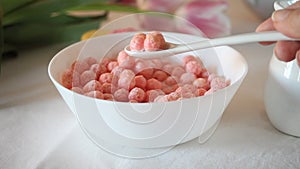 bowl with strawberry sweet corn balls. Delicious and healthy breakfast cereal. Human hand take a spoon and eating