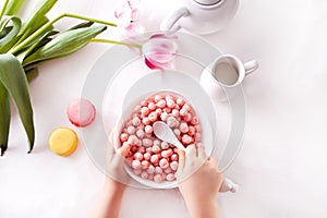 bowl with strawberry sweet corn balls. Delicious and healthy breakfast cereal. Kid hand take a spoon and eating
