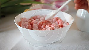 bowl with strawberry sweet corn balls. Delicious and healthy breakfast cereal. Kid hand take a spoon and eating