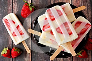 Bowl of strawberry vanilla yogurt popsicles on dark wood