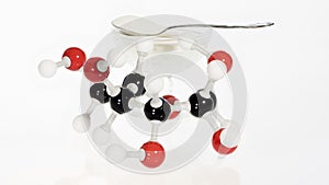 Bowl of sugar and a glucose molecule model