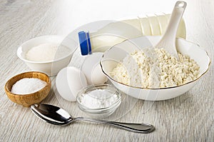 Bowl with sugar, kefir, eggs, bowl with flour, bowls with soda, salt, spoon on table