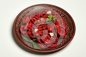 Bowl of sun dried tomatoes close-up on a white background, top view