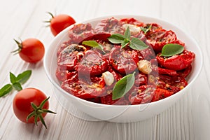 A bowl of sun-dried tomatoes in olive oil on a wooden background