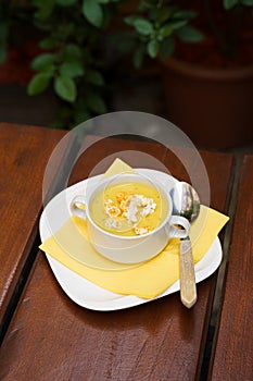 Bowl of sweet corn soup with popcorn on a wooden table