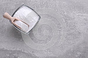 Bowl of sweet fructose powder on light grey table, top view. Space for text