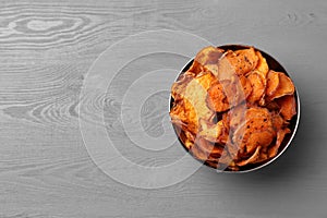 Bowl of sweet potato chips on grey table, top view