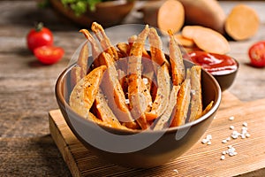 Bowl with sweet potato fries on table