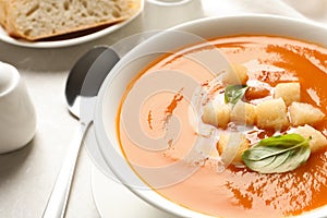 Bowl of sweet potato soup with croutons and basil served on table, closeup