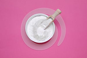 Bowl of sweet powdered fructose on pink background, top view