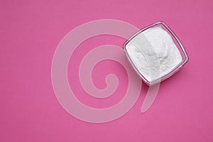 Bowl of sweet powdered fructose on pink background, top view. Space for text