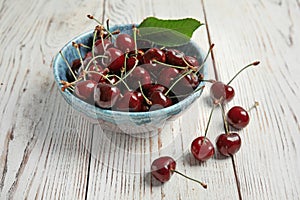 Bowl with sweet red cherries on table