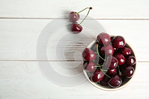 Bowl with sweet red cherries on wooden table