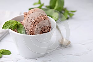 Bowl with tasty chocolate ice cream and mint leaves on white table, closeup. Space for text