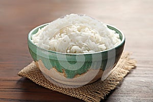 Bowl of tasty cooked white rice on wooden table