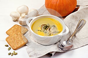 Bowl of Tasty Homemade Pumpkin Cream Soup decotated with Mushrooms and Pumpkin Seeds White Wooden Background Galette Horizontal