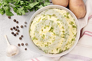 Bowl of tasty mashed potato, parsley, and pepper on grey marble table