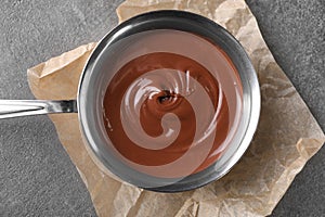 Bowl with tasty melted chocolate on grey table, top view