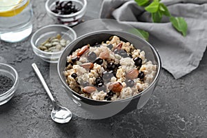 Bowl with tasty oatmeal, berries and nuts on grey textured background