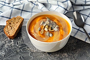 Bowl with tasty pumpkin cream soup on grey table