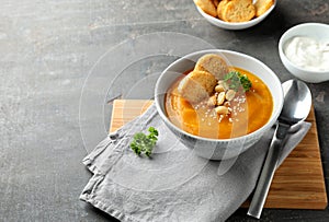 Bowl with tasty pumpkin cream soup on grey table