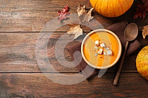 Bowl with tasty pumpkin cream soup on wooden table. Space for text