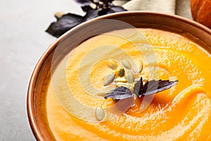Bowl with tasty pumpkin soup on gray table
