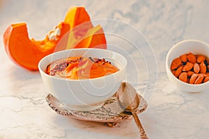 Bowl of tasty pumpkin soup ith chili flakes pepper, nuts and croutons.Space for text on marble table.Toned