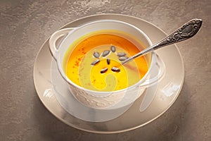 Bowl of tasty pumpkin soup and space for text on gray table, top view