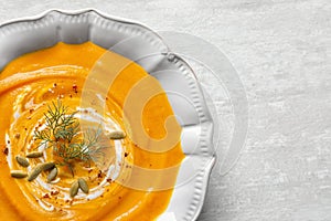 Bowl of tasty pumpkin soup and space for text on table