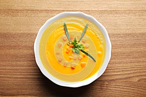 Bowl with tasty pumpkin soup on wooden table