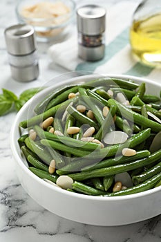 Bowl of tasty salad with green beans on white marble table