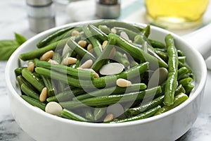 Bowl of tasty salad with green beans on white marble table, closeup