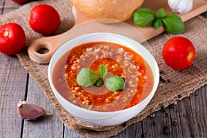 Bowl with tasty tomato soup on wooden board