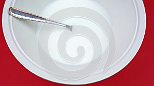 Bowl with tasty yogurt and spoon on red background closeup