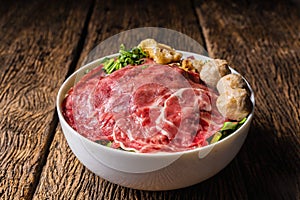 Bowl of Thai style beef noodle with fresh sliced beef and fresh sliced ox shank and meatball and stewed beef on wooden table