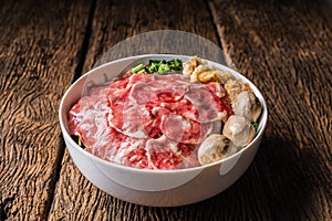 Bowl of Thai style beef noodle with fresh sliced ox shank and meatball on wooden table