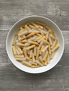 A bowl of tortiglioni pasta against a wooden background