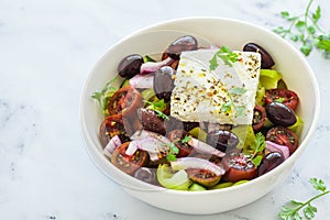 Bowl of traditional Greek salad with tomatoes, cucumbers, red onions, kalamata olives, feta sheep cheese and olive oil