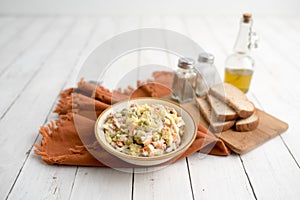 Bowl of traditional Russian salad called Olivie, Russian New Year or Christmas salad on wooden background.